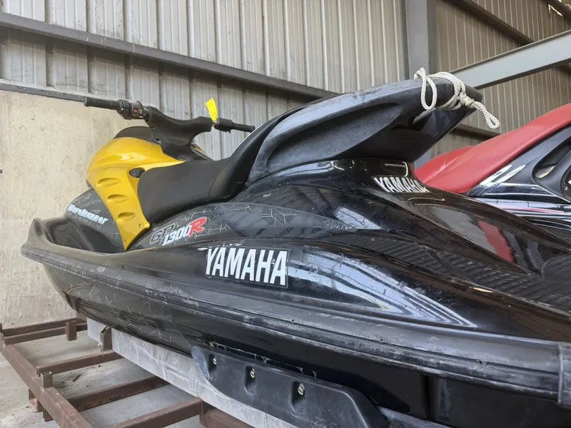 Slide: The Image of A 2006 Yamaha GP1300R jet ski is in a storage area. It features a black and yellow design. - 12