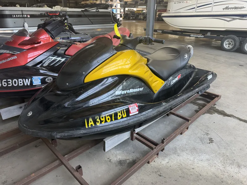 The Image of A black and yellow 2006 Yamaha GP1300R jet ski is parked in a warehouse. - 1