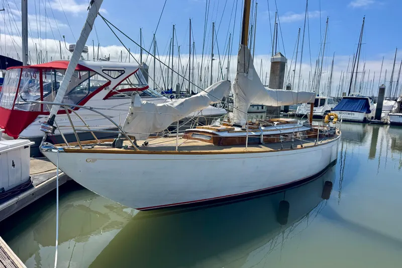 Slide: The Image of 1955 Henry R Hinckley Owens Cutter sailboat docked in a marina, surrounded by other boats. - 2