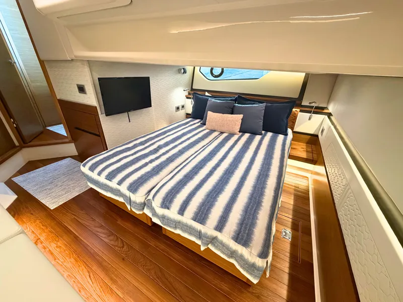 Slide: The Image of The 2025 Tiara Yachts 48 LE cabin features an elegant double bed with striped bedding. - 27