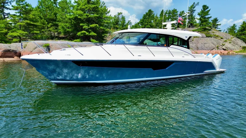 Slide: The Image of 2025 Tiara Yachts 48 LE on calm water, surrounded by trees and rocks. - 2