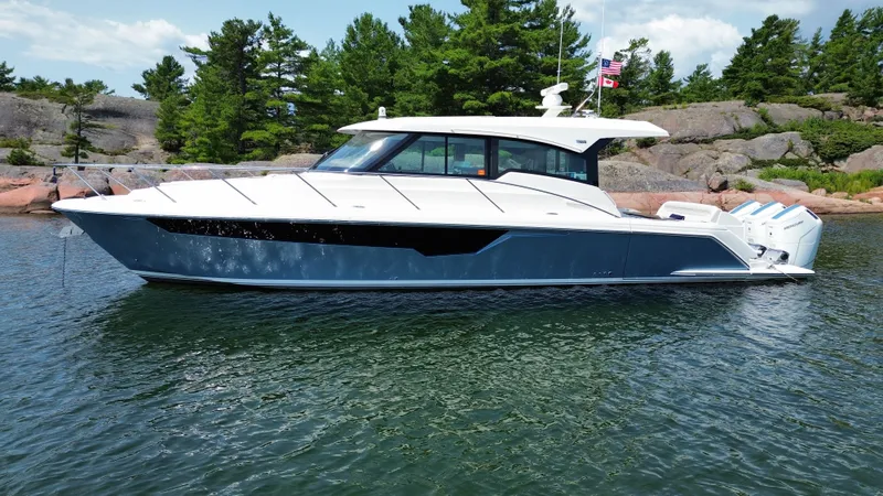 Slide: The Image of 2025 Tiara Yachts 48 LE on calm water, surrounded by trees and rocks. - 3