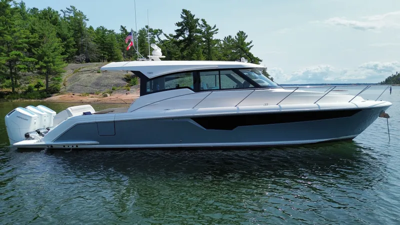 Slide: The Image of 2025 Tiara Yachts 48 LE on calm water, surrounded by trees and rocks. - 1