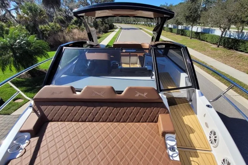 Slide: The Image of 2023 NX Boats 340 Sport Coupe with luxurious seating and sleek design on a sunny day. - 17