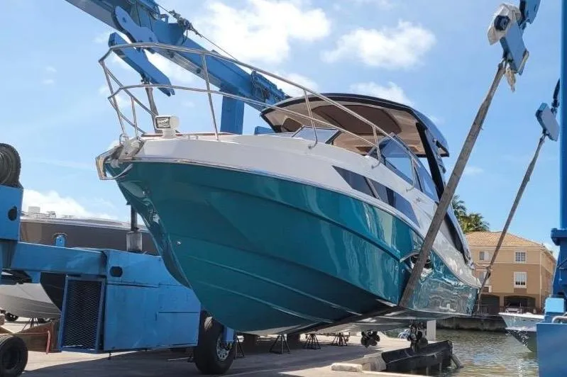 Slide: The Image of A 2023 NX Boats 340 Sport Coupe being lowered into the water by a crane. - 6