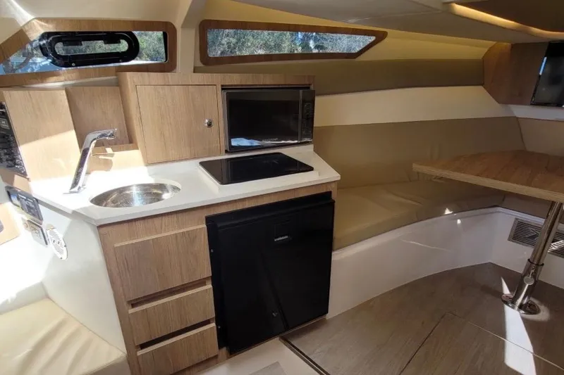 Slide: The Image of 2023 NX Boats 340 Sport Coupe interior with kitchenette and seating area. - 20