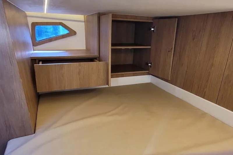 Slide: The Image of 2023 NX Boats 340 Sport Coupe cabin interior with wooden storage and window. - 25