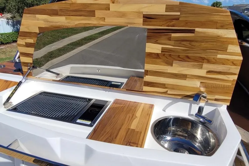Slide: The Image of 2023 NX Boats 340 Sport Coupe kitchen area with wooden accents and stainless steel sink. - 13