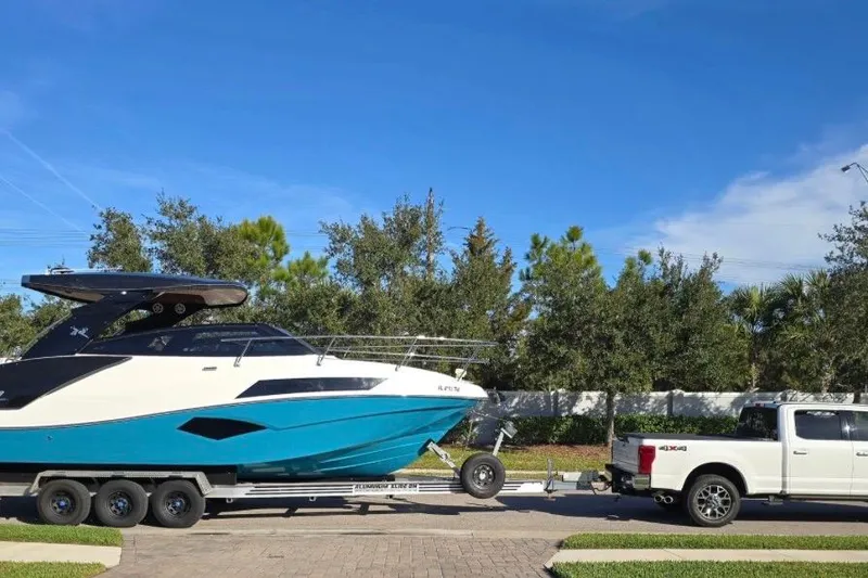 Slide: The Image of 2023 NX Boats 340 Sport Coupe on trailer, towed by a white truck. - 2