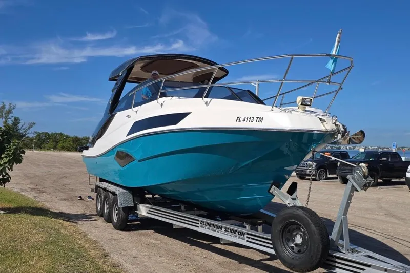 Slide: The Image of 2023 NX Boats 340 Sport Coupe on trailer under clear blue sky. - 1