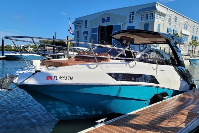The Image of 2023 NX Boats 340 Sport Coupe docked at marina, showcasing sleek design and modern features. - 3