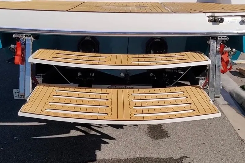 Slide: The Image of 2023 NX Boats 340 Sport Coupe swim platform with teak finish, docked on pavement. - 9