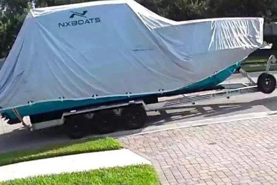 Slide: The Image of 2023 NX Boats 340 Sport Coupe covered on trailer, parked on brick driveway. - 11