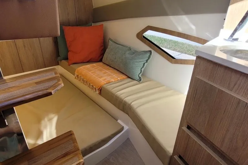Slide: The Image of Interior of 2023 NX Boats 340 Sport Coupe with cozy seating and colorful cushions. - 23