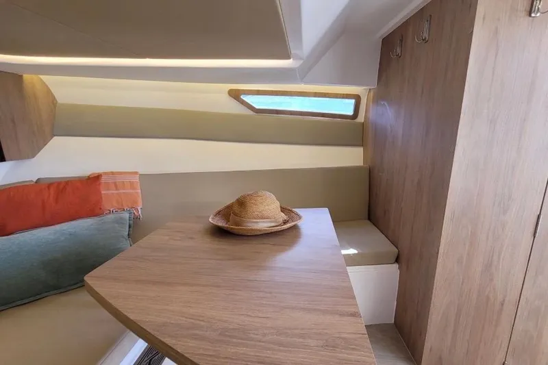 Slide: The Image of Interior of 2023 NX Boats 340 Sport Coupe with cozy seating and wooden table. - 19
