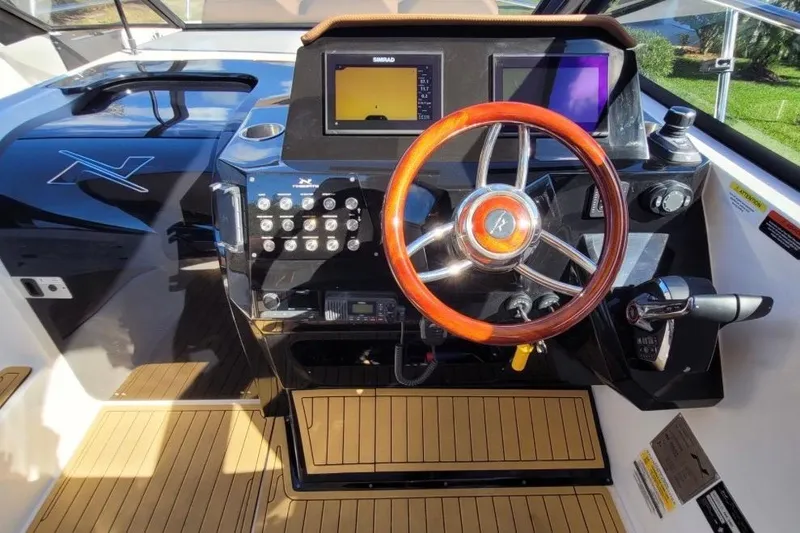 Slide: The Image of 2023 NX Boats 340 Sport Coupe helm with wooden steering wheel and modern controls. - 18