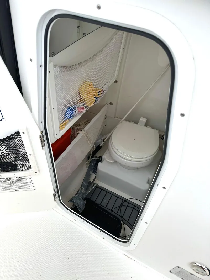 Slide: The Image of 2022 Sea Hunt Ultra 255 SE boat interior with compact marine toilet and storage. - 23