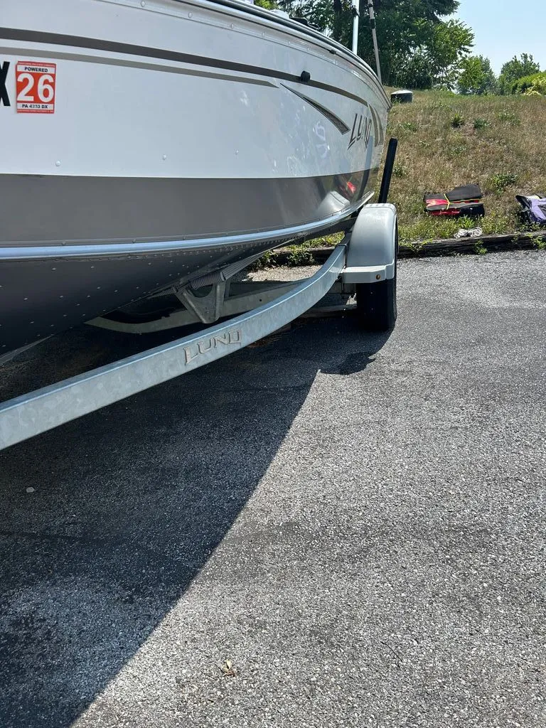 Slide: The Image of A 2019 Lund 1675 Impact SS boat on a trailer, parked on a paved area. - 17