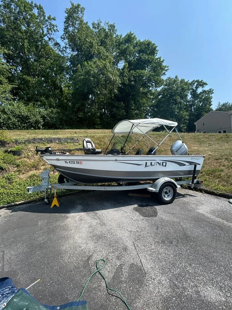 The Image of A 2019 Lund 1675 Impact SS boat on a trailer in a driveway. - 0