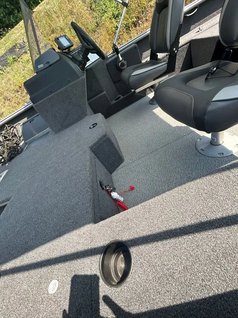 Slide: The Image of The image shows the interior of a 2019 Lund 1675 Impact SS boat with gray carpeting. - 3