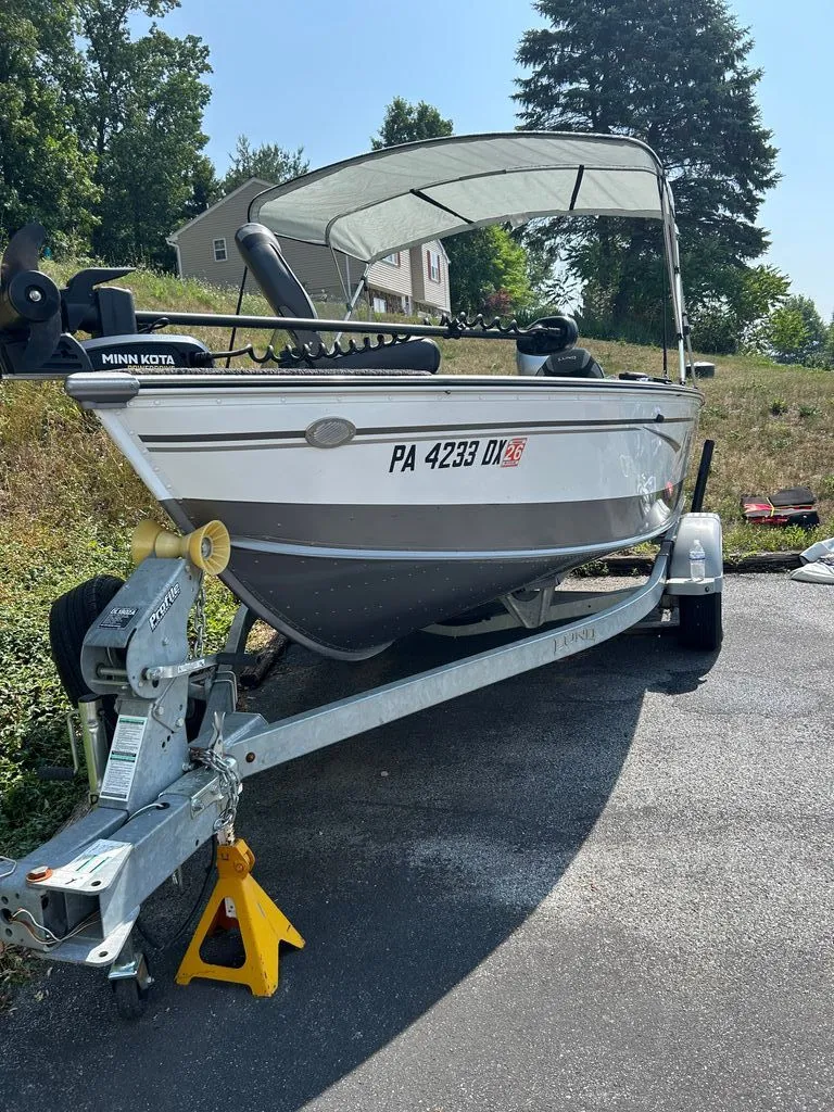 Slide: The Image of A 2019 Lund 1675 Impact SS boat on a trailer, parked on a driveway. - 1