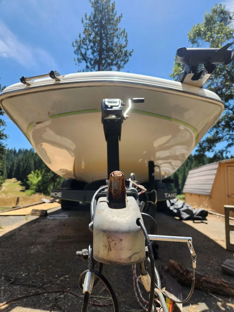 Slide: The Image of A 2018 Tahoe 2150 CC boat on a trailer, surrounded by trees and a blue sky. - 1