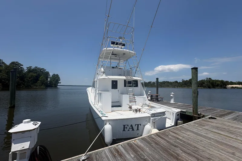 Slide: The Image of 1973 Hatteras 53 Convertible yacht docked on a serene lake under clear skies. - 90