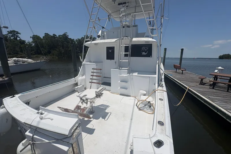 Slide: The Image of 1973 Hatteras 53 Convertible boat docked, featuring spacious deck and fishing chair. - 97