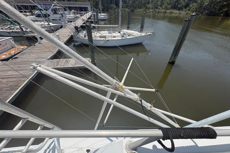 Slide: The Image of 1973 Hatteras 53 Convertible yacht docked at marina, surrounded by calm water and other boats. - 86
