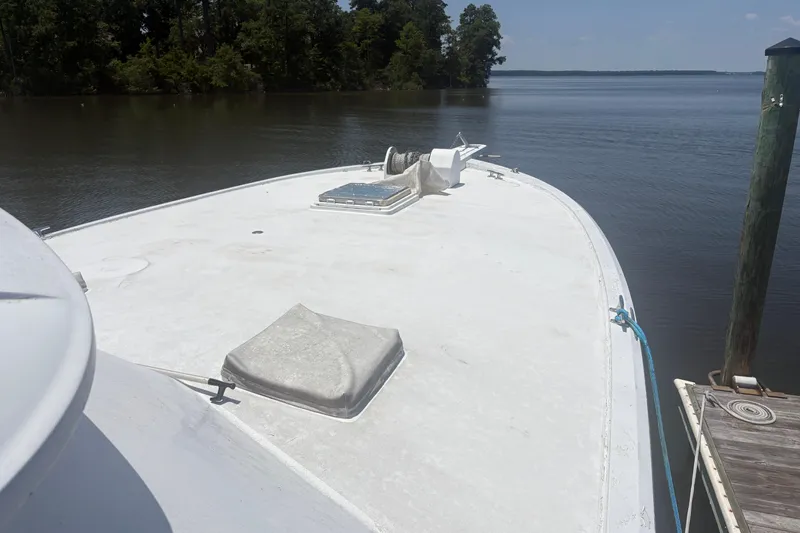 Slide: The Image of 1973 Hatteras 53 Convertible yacht docked by a serene lake with lush trees. - 88