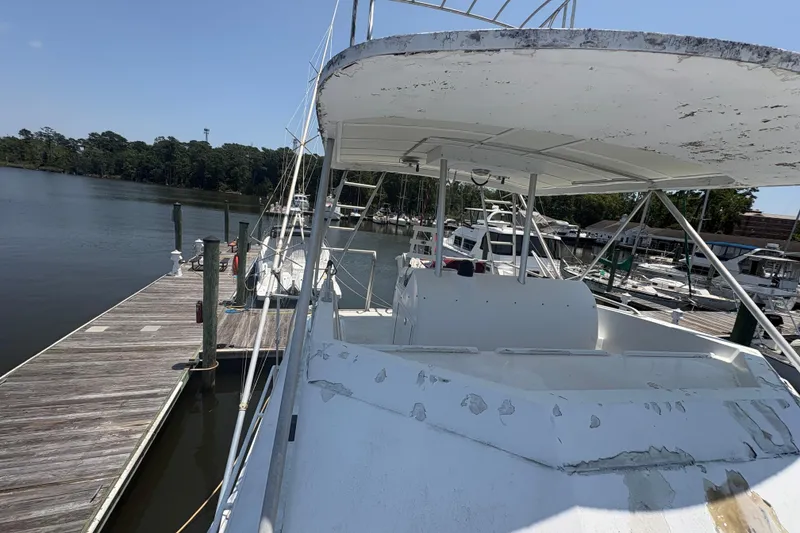 Slide: The Image of 1973 Hatteras 53 Convertible yacht docked at a marina, showing weathered exterior. - 80