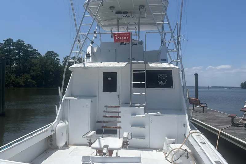Slide: The Image of 1973 Hatteras 53 Convertible yacht for sale, docked by a serene waterfront. - 6