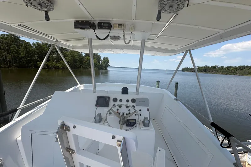 Slide: The Image of Helm of 1973 Hatteras 53 Convertible yacht overlooking serene water and lush shoreline. - 68