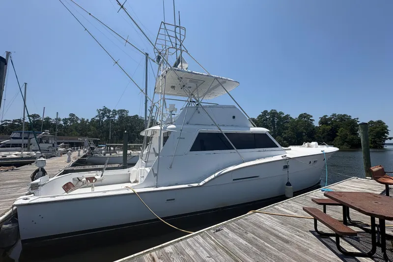 Slide: The Image of 1973 Hatteras 53 Convertible yacht docked at a marina under clear blue skies. - 92