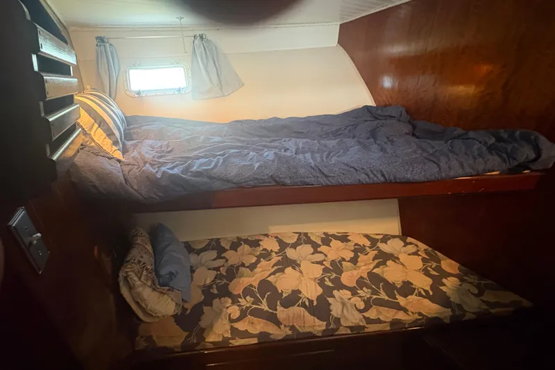 Slide: The Image of Cozy cabin bunk beds in a 1973 Hatteras 53 Convertible yacht, featuring floral and striped bedding. - 35