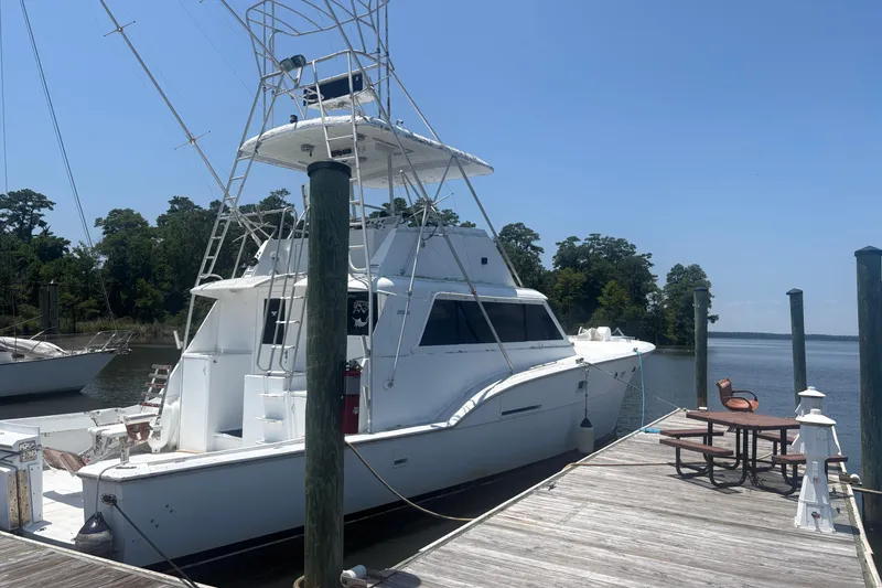 Slide: The Image of 1973 Hatteras 53 Convertible yacht docked by a serene waterfront. - 94