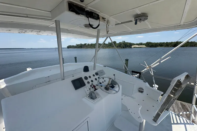Slide: The Image of Helm of 1973 Hatteras 53 Convertible yacht overlooking serene waters and distant shoreline. - 73