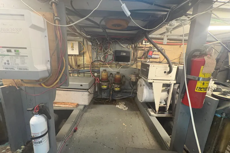 Slide: The Image of Engine room of a 1973 Hatteras 53 Convertible boat, featuring wiring and equipment. - 104