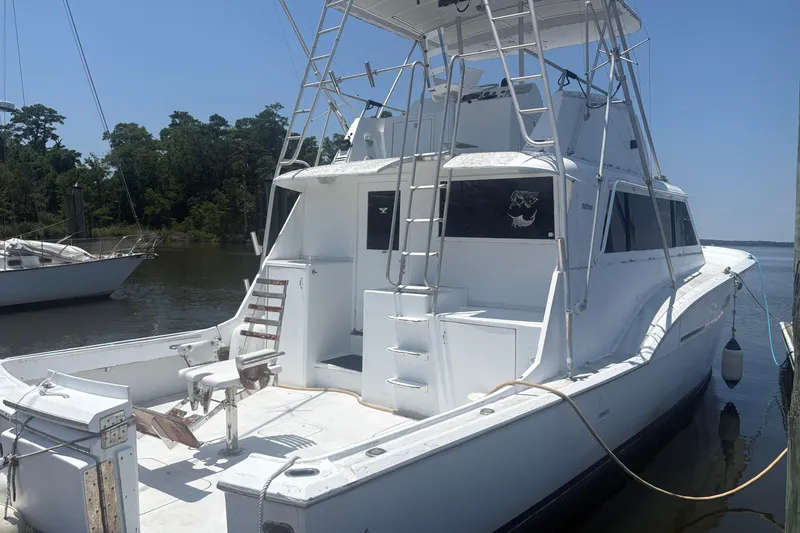 Slide: The Image of 1973 Hatteras 53 Convertible yacht docked by a serene riverside. - 64