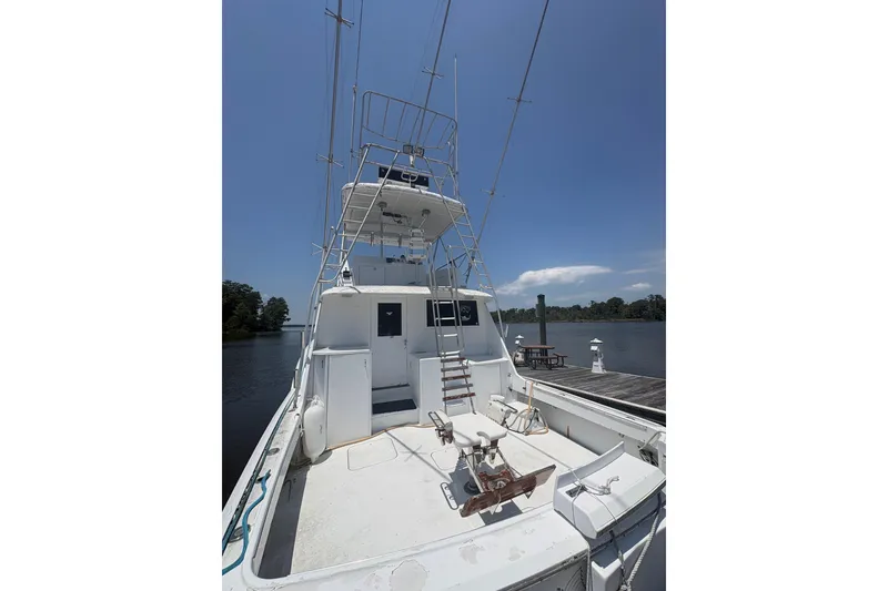 Slide: The Image of 1973 Hatteras 53 Convertible yacht docked by a serene river under clear blue skies. - 11