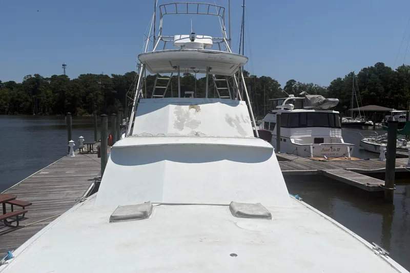 Slide: The Image of 1973 Hatteras 53 Convertible yacht docked at a marina, surrounded by trees and water. - 76