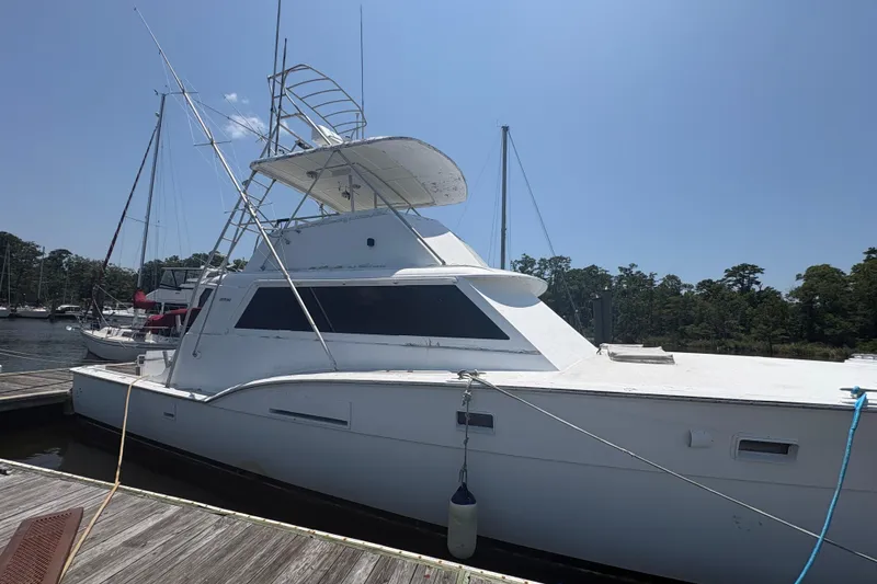 Slide: The Image of 1973 Hatteras 53 Convertible yacht docked at a marina under clear blue sky. - 94