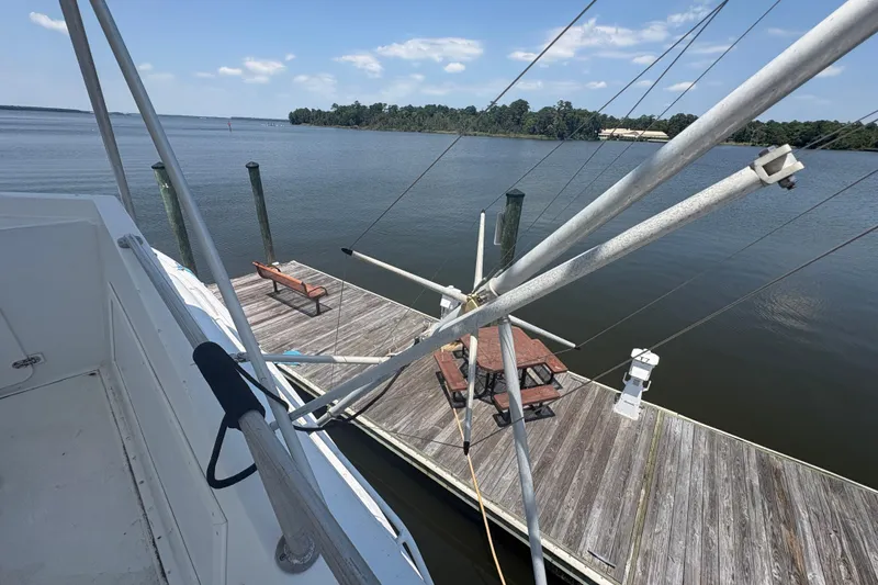 Slide: The Image of 1973 Hatteras 53 Convertible yacht docked by a serene lake under a clear blue sky. - 86