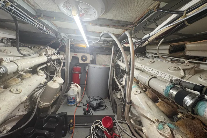 Slide: The Image of Engine room of a 1973 Hatteras 53 Convertible yacht, featuring diesel engines and maintenance equipment. - 99