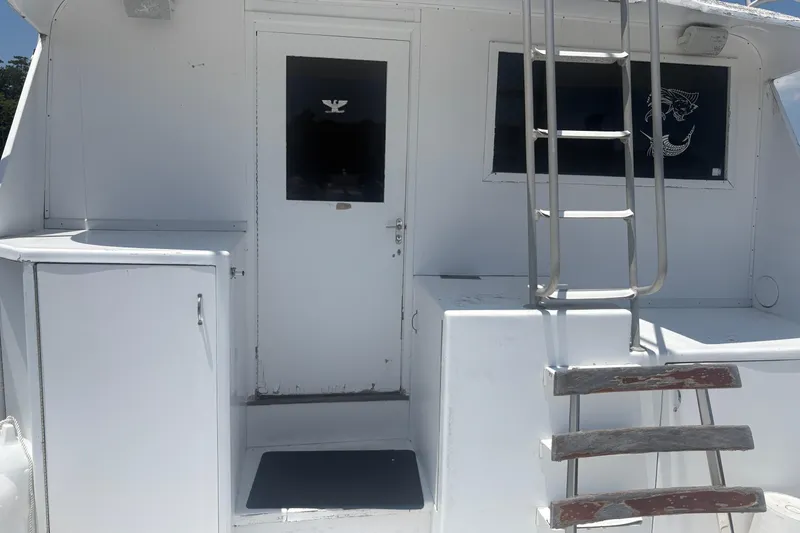 Slide: The Image of 1973 Hatteras 53 Convertible yacht stern with ladder and door, showcasing classic design. - 13