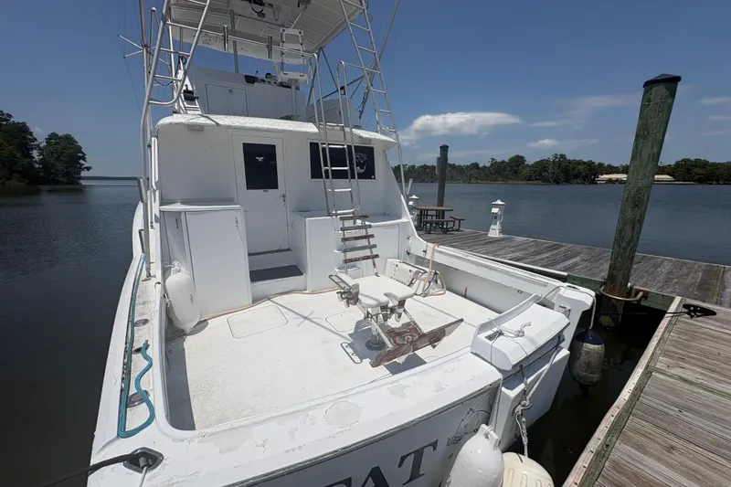 Slide: The Image of 1973 Hatteras 53 Convertible yacht docked by a serene waterfront. - 65