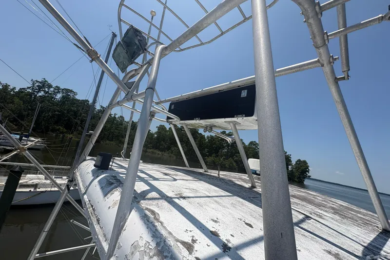 Slide: The Image of 1973 Hatteras 53 Convertible boat deck with metal framework, docked near trees and water. - 83