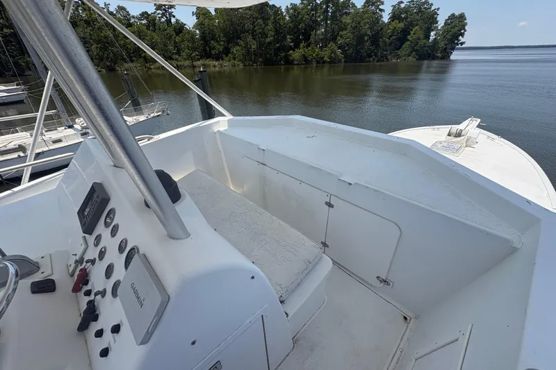 Slide: The Image of 1973 Hatteras 53 Convertible yacht helm with control panel, overlooking serene water and lush greenery. - 73