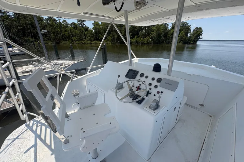 Slide: The Image of Helm of 1973 Hatteras 53 Convertible yacht with steering wheel and controls, docked by a serene lake. - 66