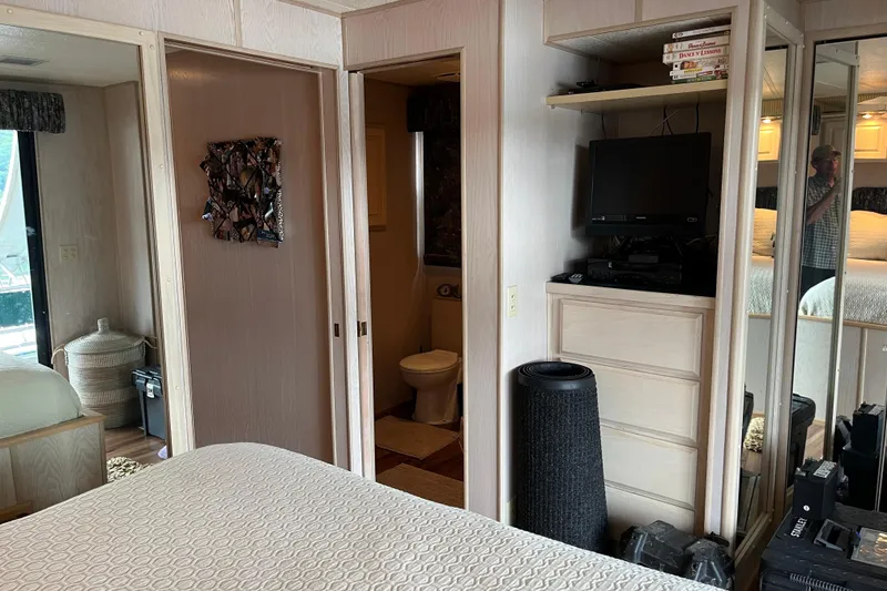Slide: The Image of Interior of a 1997 Lakeview 65x18 houseboat bedroom with TV, dresser, and bathroom. - 22
